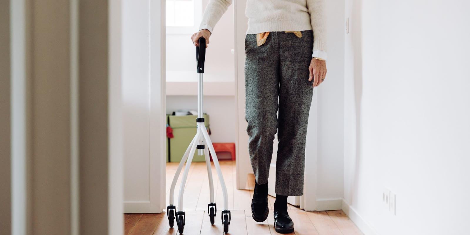 An older adult walking with a rollator along a hallway at home