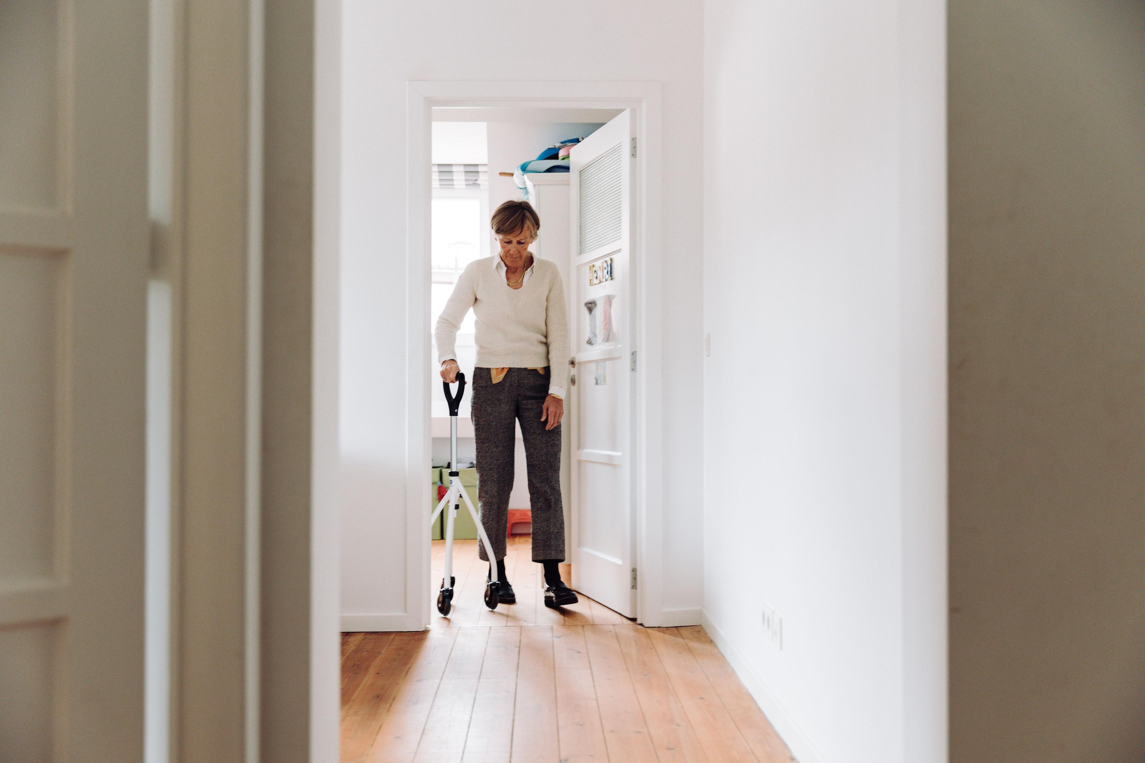 Elderly woman using a rollator walker at home, representing home visit physiotherapy in Dublin
